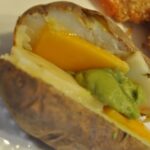 Baked potato with toppings of cheese and guacamole.