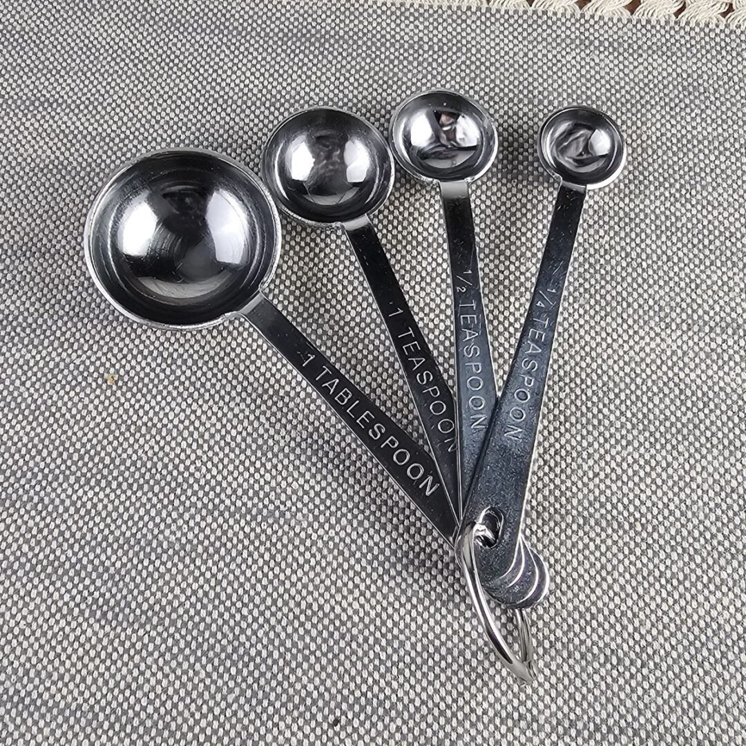 Set of metal measuring spoons on a placemat.